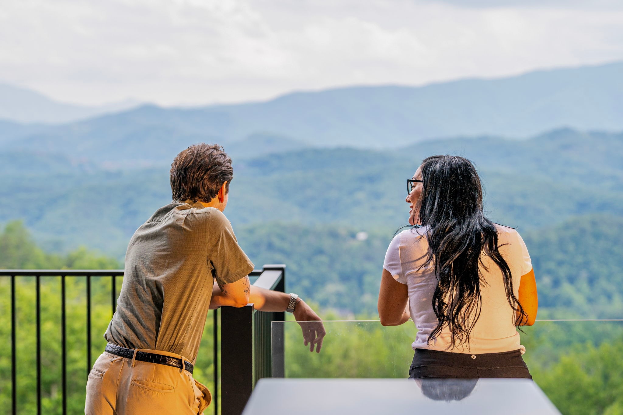 Couple on the deck balcony overlooking Smoky Mountain views at Excalibur Lodge
