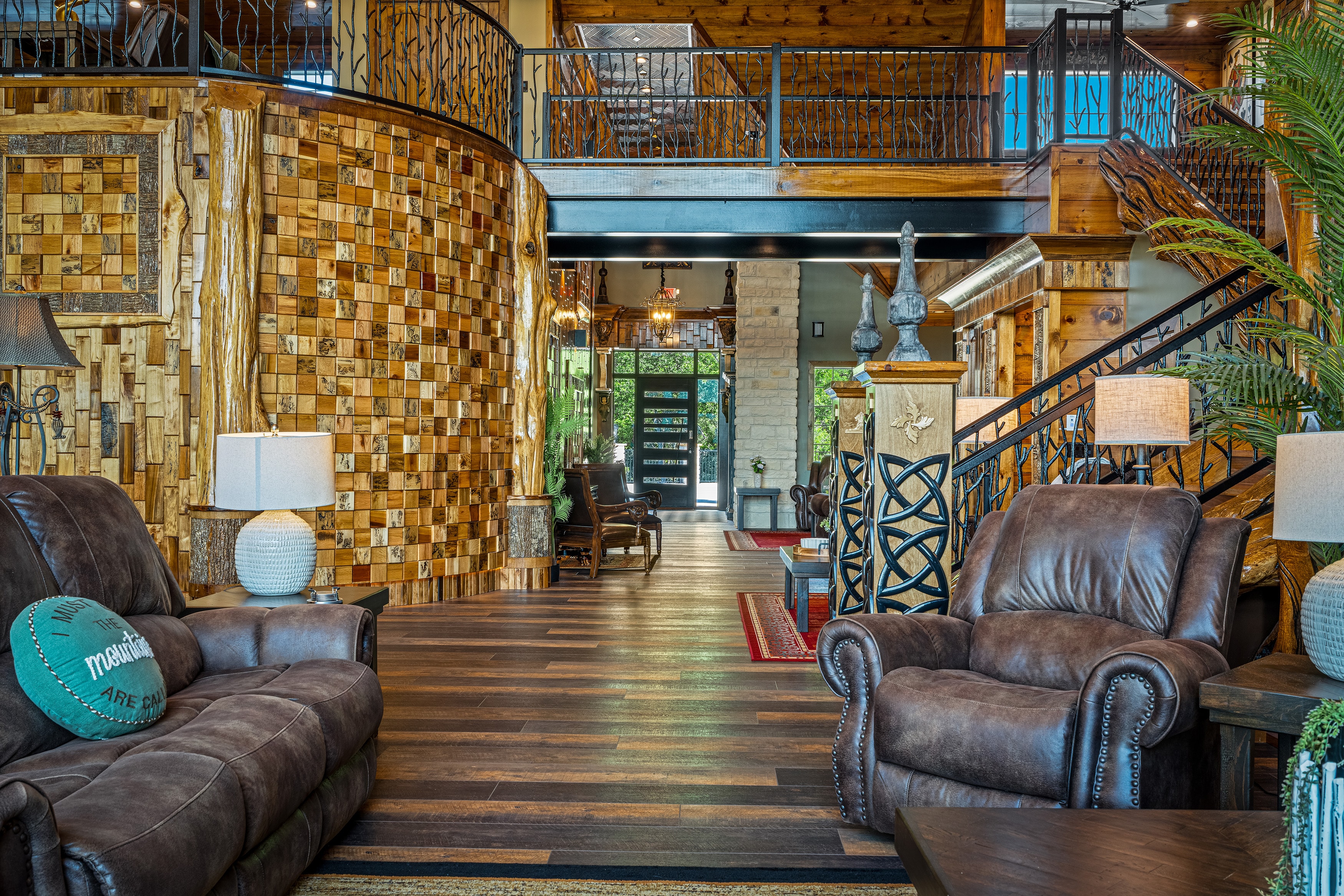Excalibur grand entry foyer with mosaic wood tile curved wall, wrought iron staircase, and leather seating